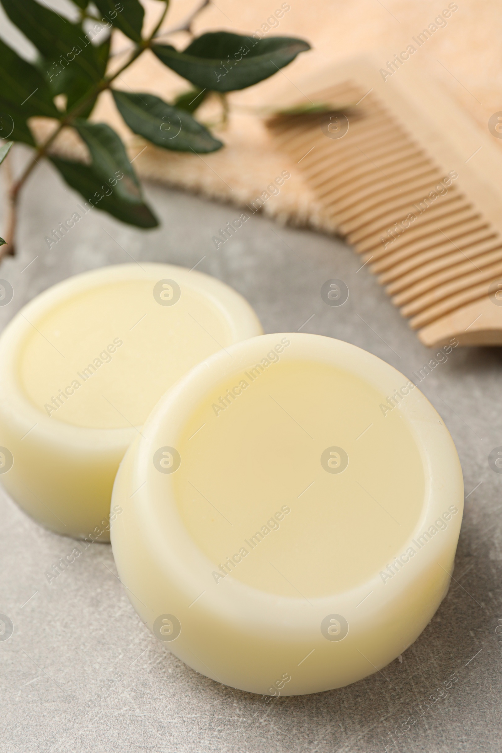 Photo of Solid shampoo bars, green twig and comb on grey table