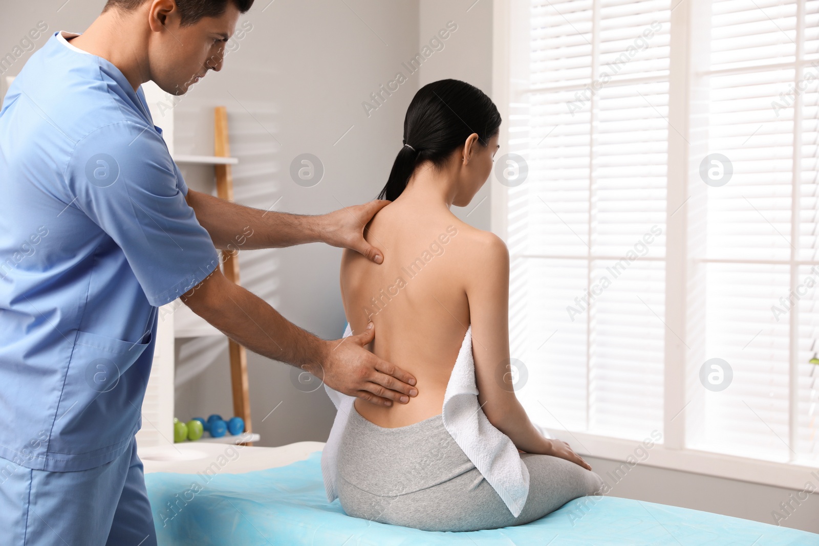 Photo of Orthopedist examining woman's back in clinic. Scoliosis treatment