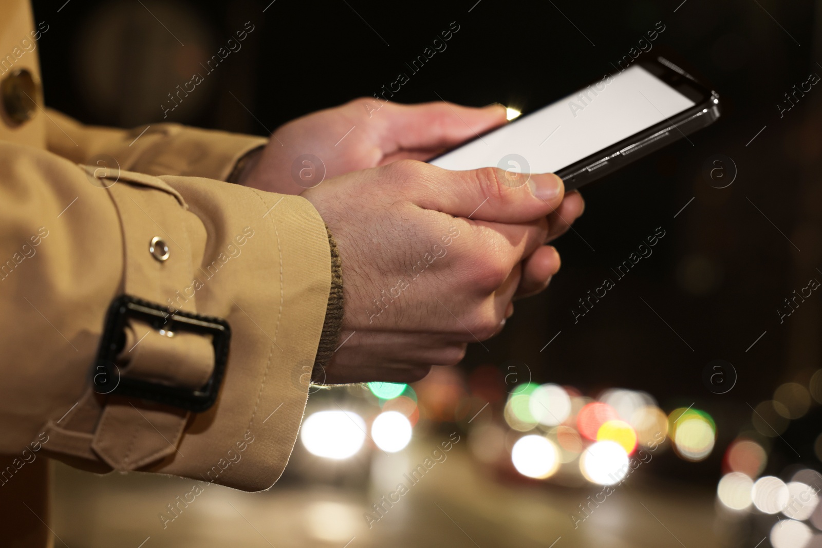 Photo of Man using smartphone on night city street, closeup