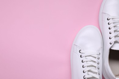 Photo of Pair of stylish white sneakers on pink background, top view. Space for text