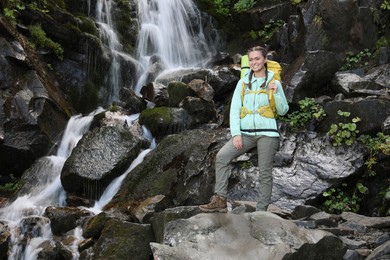 Photo of Happy tourist with backpack near mountain waterfall