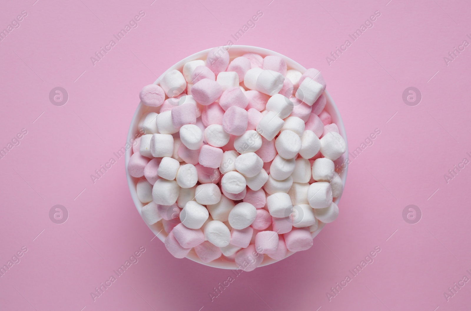 Photo of Bowl with delicious marshmallows on pink background, top view