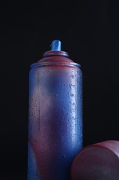 Photo of One spray paint can with cap on dark background