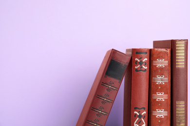 Photo of Collection of old books on violet background, space for text