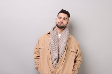 Photo of Smiling man in warm scarf on light grey background