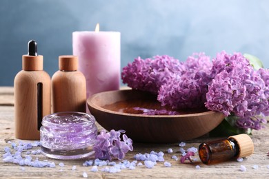 Photo of Cosmetic products and lilac flowers on wooden table