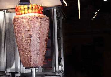 Photo of Vertical rotisserie with roasted meat in street cafe