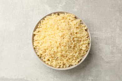 Delicious bulgur in bowl on gray table, top view