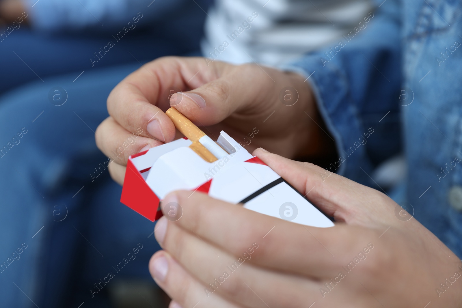 Photo of Man taking cigarette out of pack outdoors, closeup