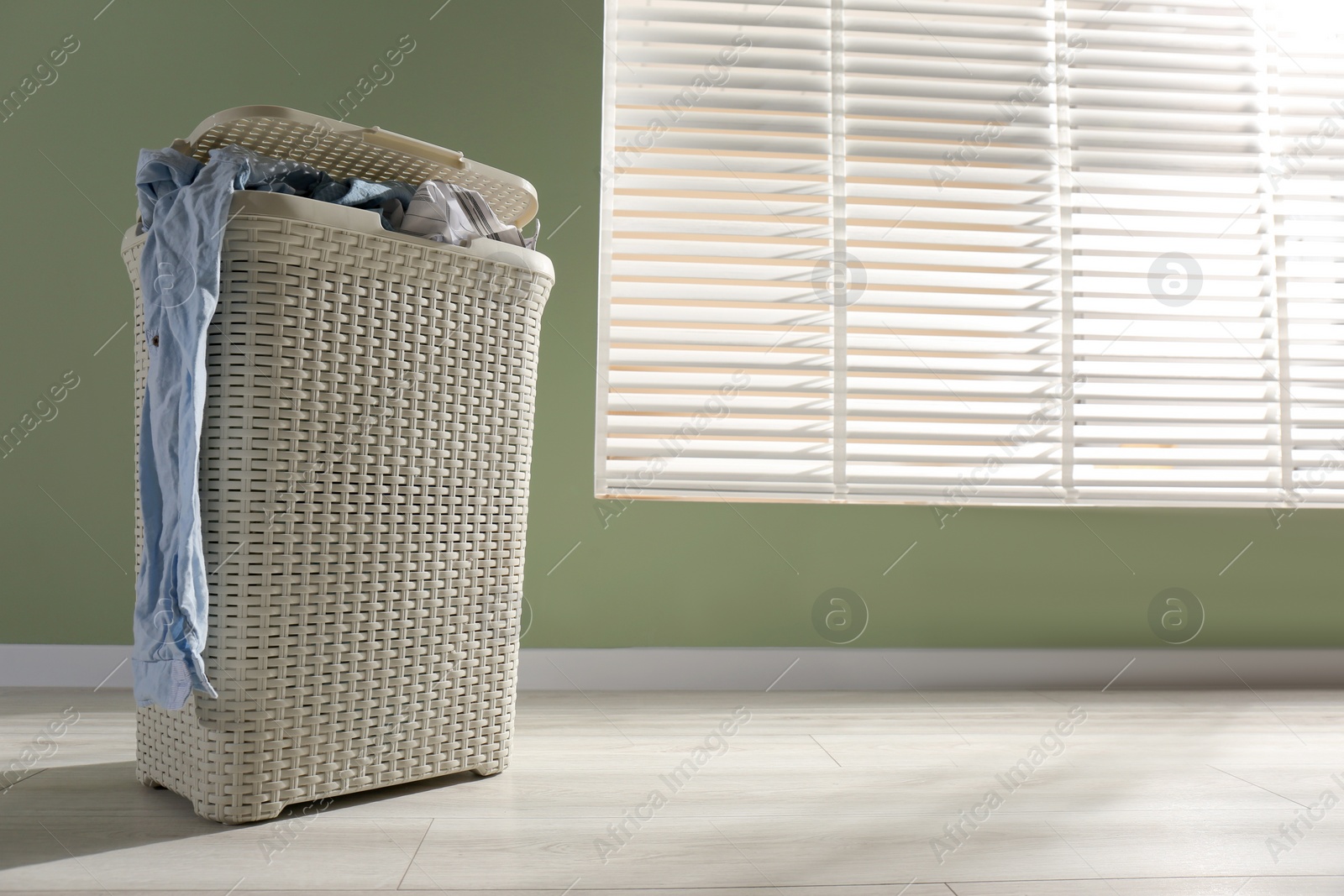 Photo of Laundry basket with clothes near window indoors. Space for text