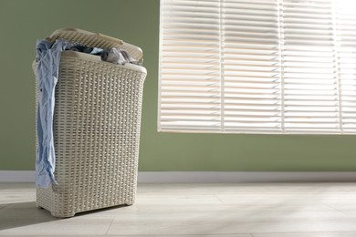 Photo of Laundry basket with clothes near window indoors. Space for text