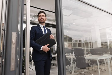 Photo of Male real estate agent with leather portfolio outside office