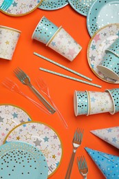Photo of Disposable tableware on orange background, flat lay