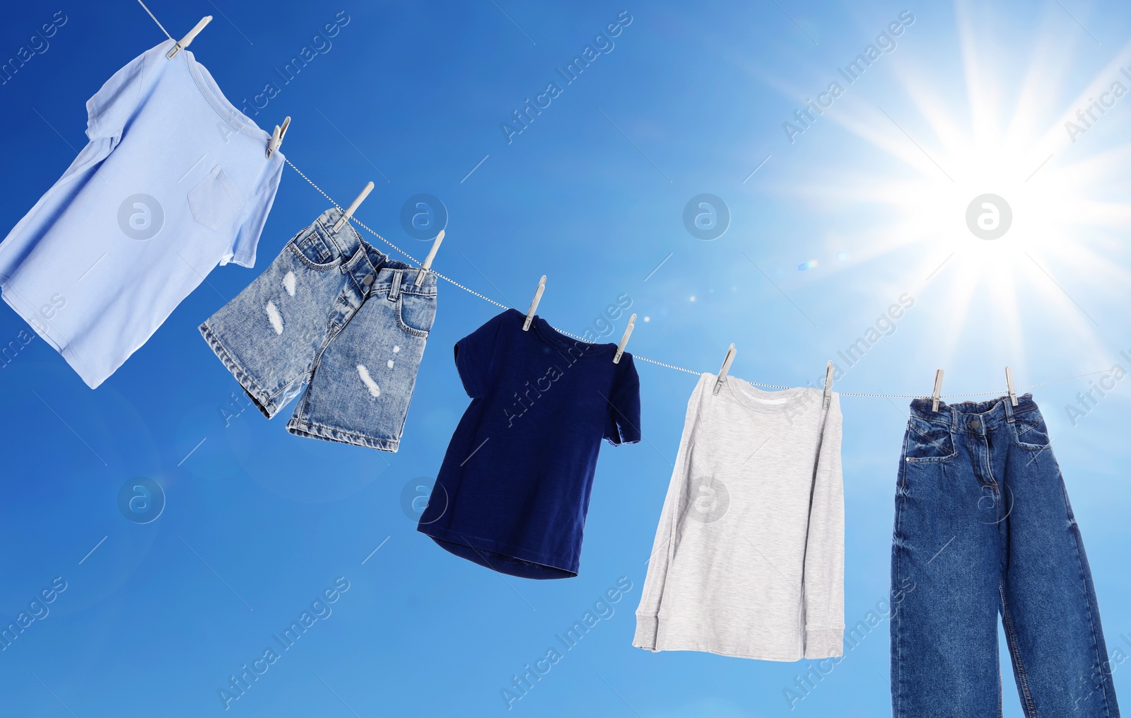 Image of Different clothes drying on washing line against blue sky