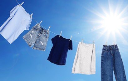 Image of Different clothes drying on washing line against blue sky