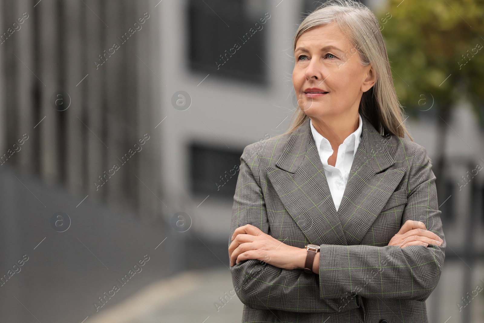 Photo of Beautiful woman with crossed arms outdoors, space for text. Lawyer, businesswoman, accountant or manager