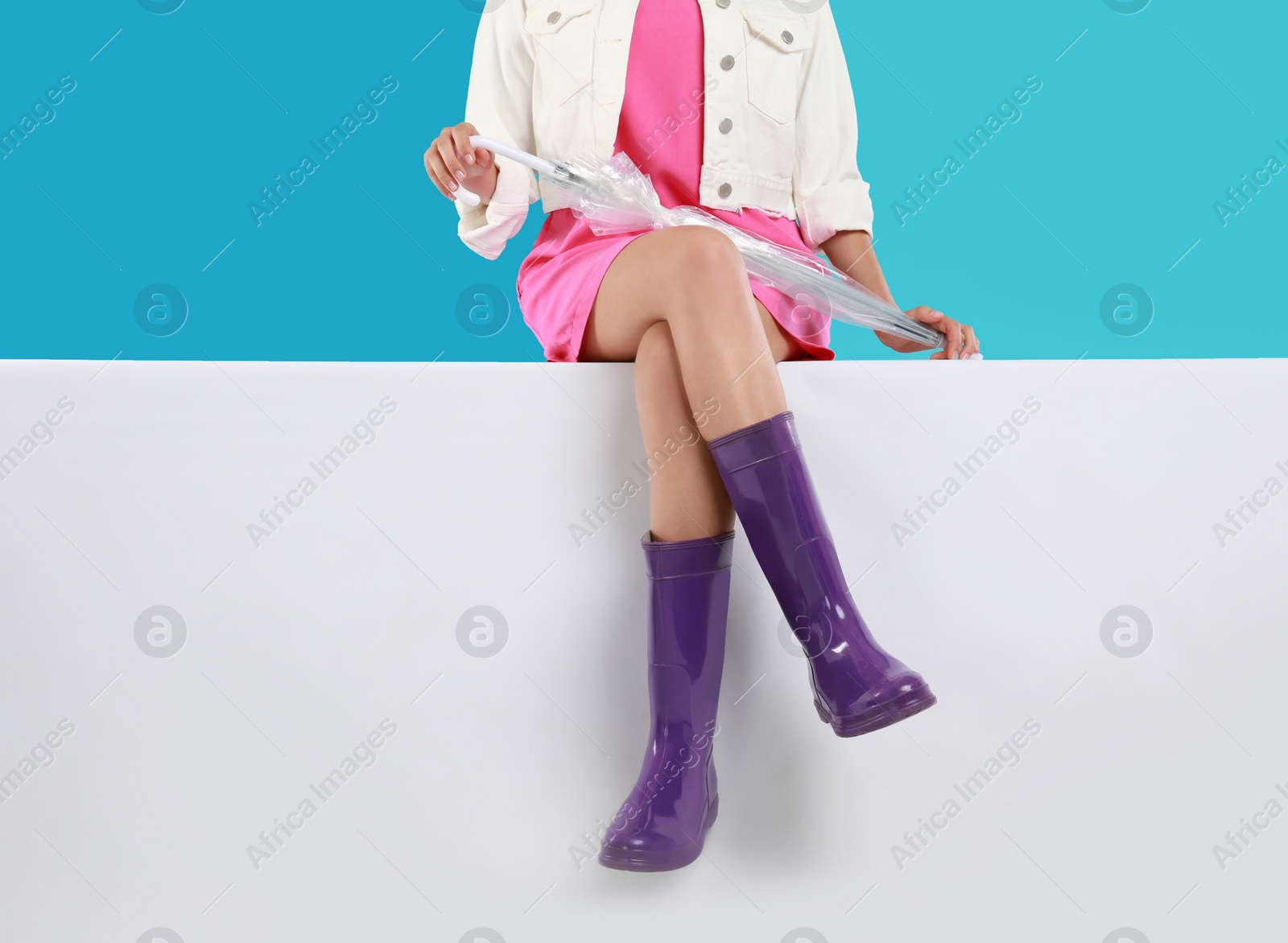 Photo of Woman wearing gumboots on color background, closeup. Stylish rubber shoes