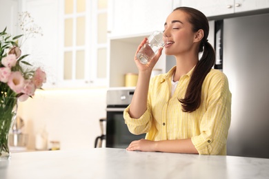 Photo of Young woman drinking pure water from glass indoors, closeup
