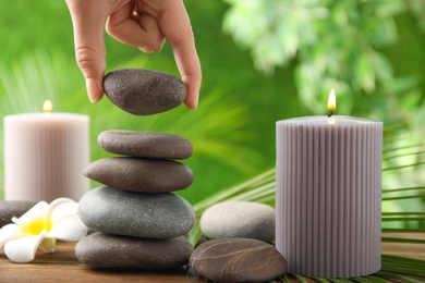 Photo of Woman stacking stones on table against blurred background, closeup. Zen concept