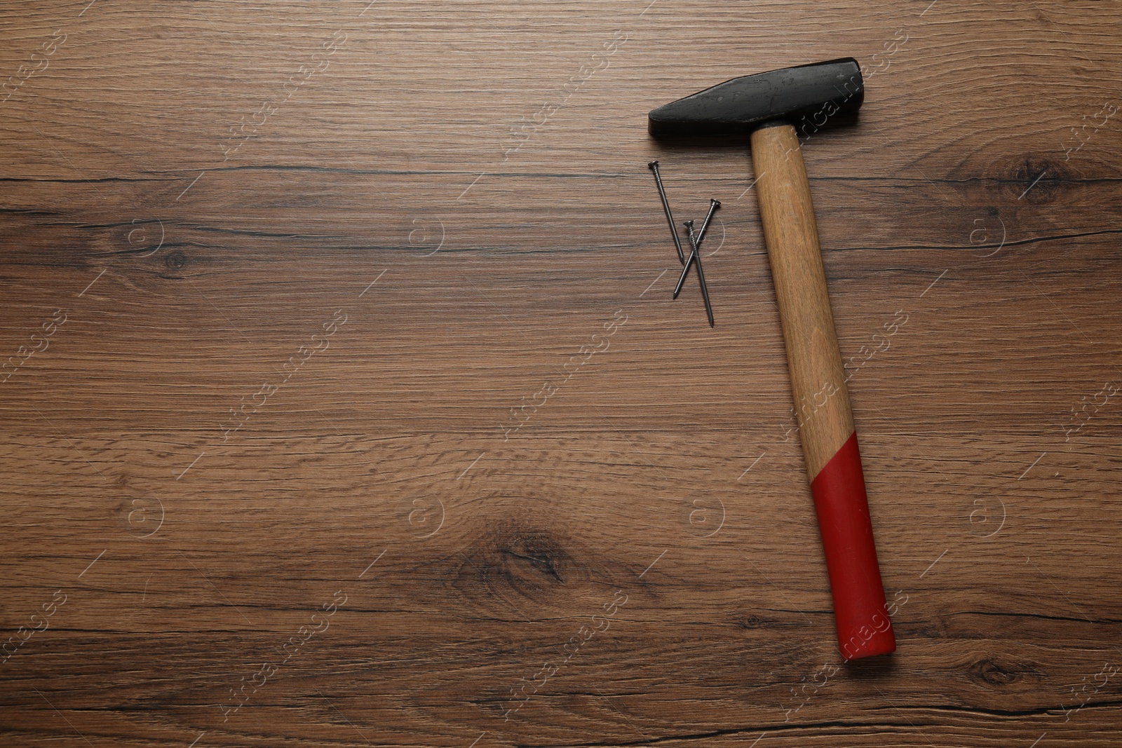 Photo of Hammer and metal nails on wooden table, top view. Space for text