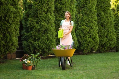 Photo of Happy young woman watering plants in garden