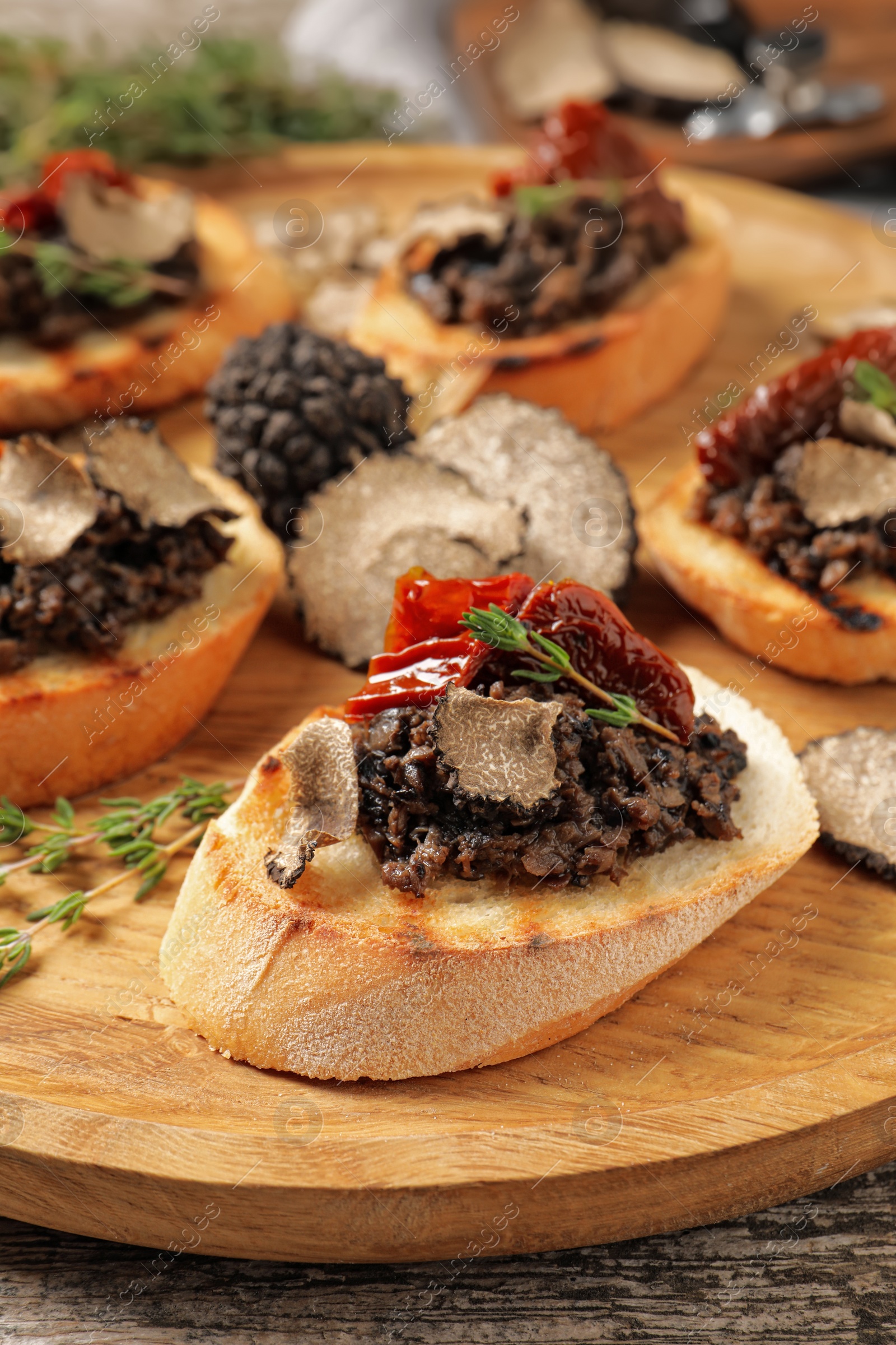 Photo of Delicious bruschettas with truffle sauce and sun dried tomatoes on wooden table, closeup