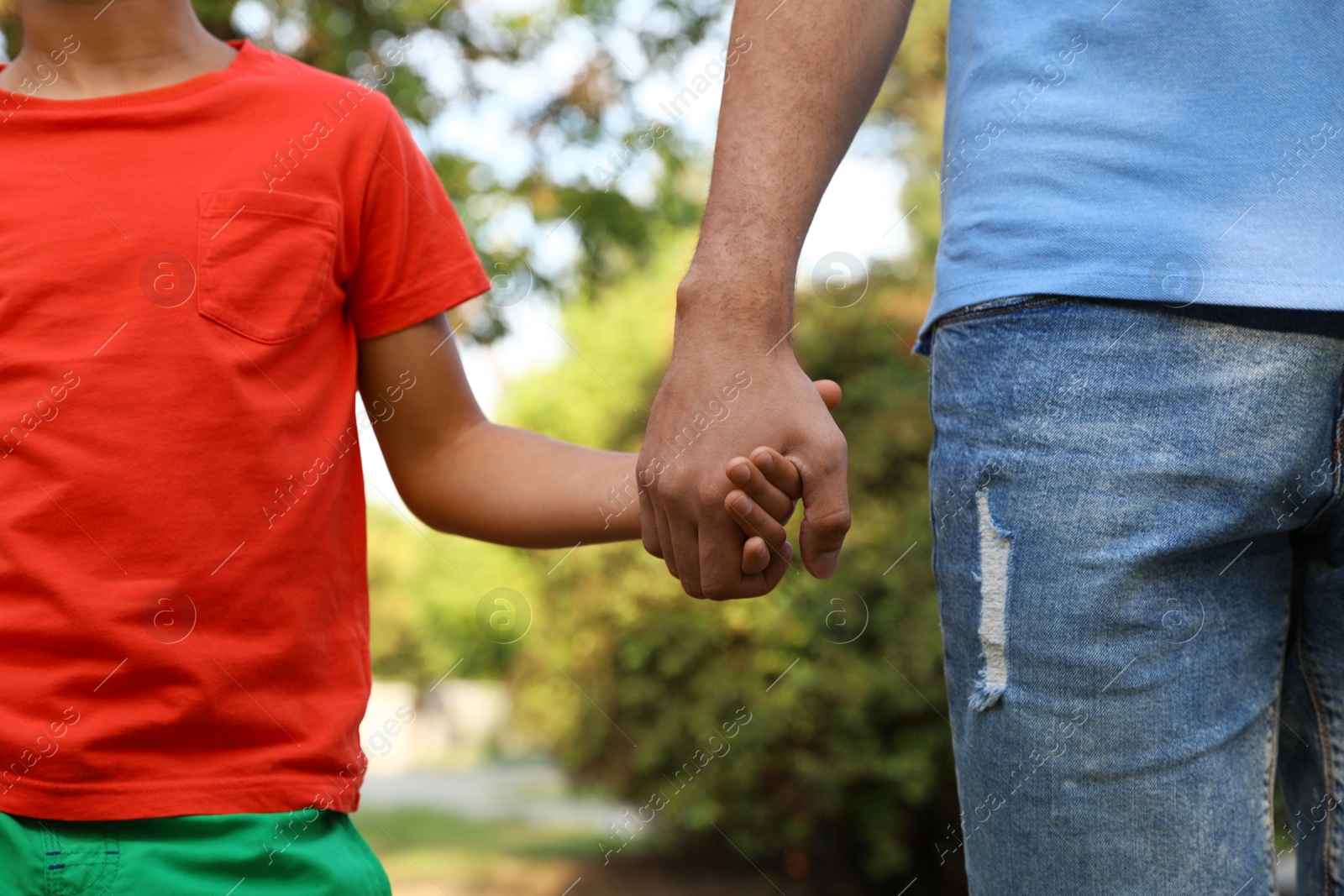 Photo of Little boy and his father holding hands outdoors, closeup. Family weekend