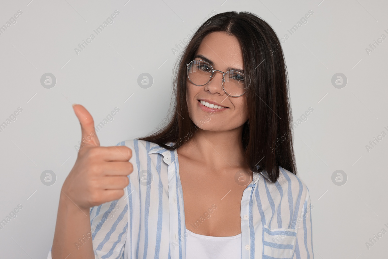 Photo of Young woman showing thumb up on white background