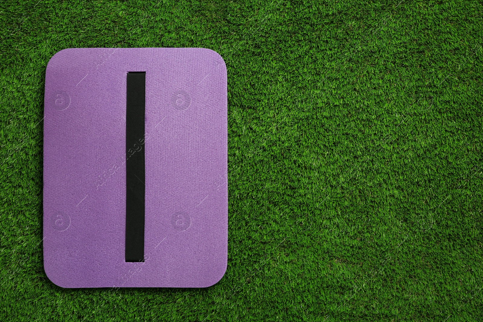 Photo of Violet foam tourist seat mat on green grass, top view. Space for text