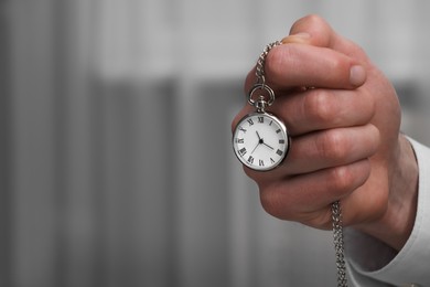 Photo of Man holding chain with elegant pocket watch, closeup. Space for text