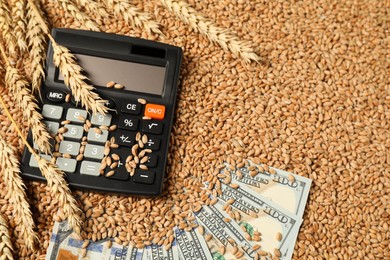 Photo of Dollar banknotes, calculator and wheat ears on grains, above view. Agricultural business