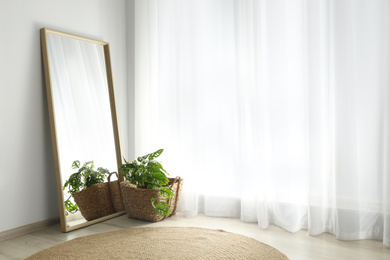 Photo of Large mirror with wooden frame near window in light room