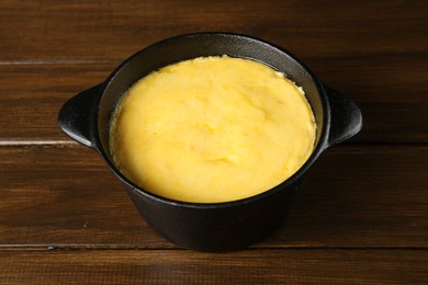 Photo of Fondue pot with melted cheese on wooden table