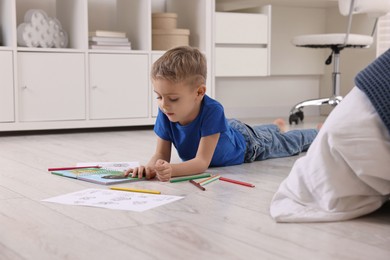 Cute little boy reading book on warm floor at home. Heating system