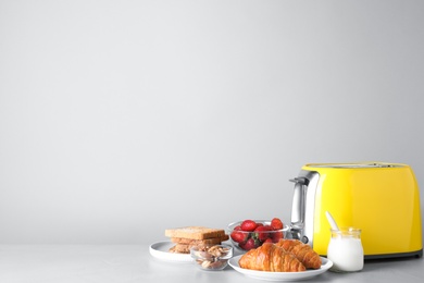 Photo of Healthy breakfast and modern toaster on light grey table, space for text