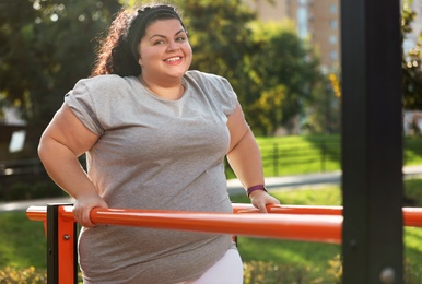 Beautiful overweight woman training on sports ground