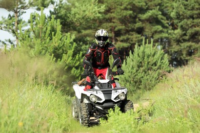 Photo of Man driving modern quad bike on road near forest. Extreme sport