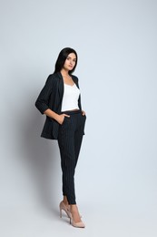 Photo of Full length portrait of beautiful woman in formal suit on light background. Business attire