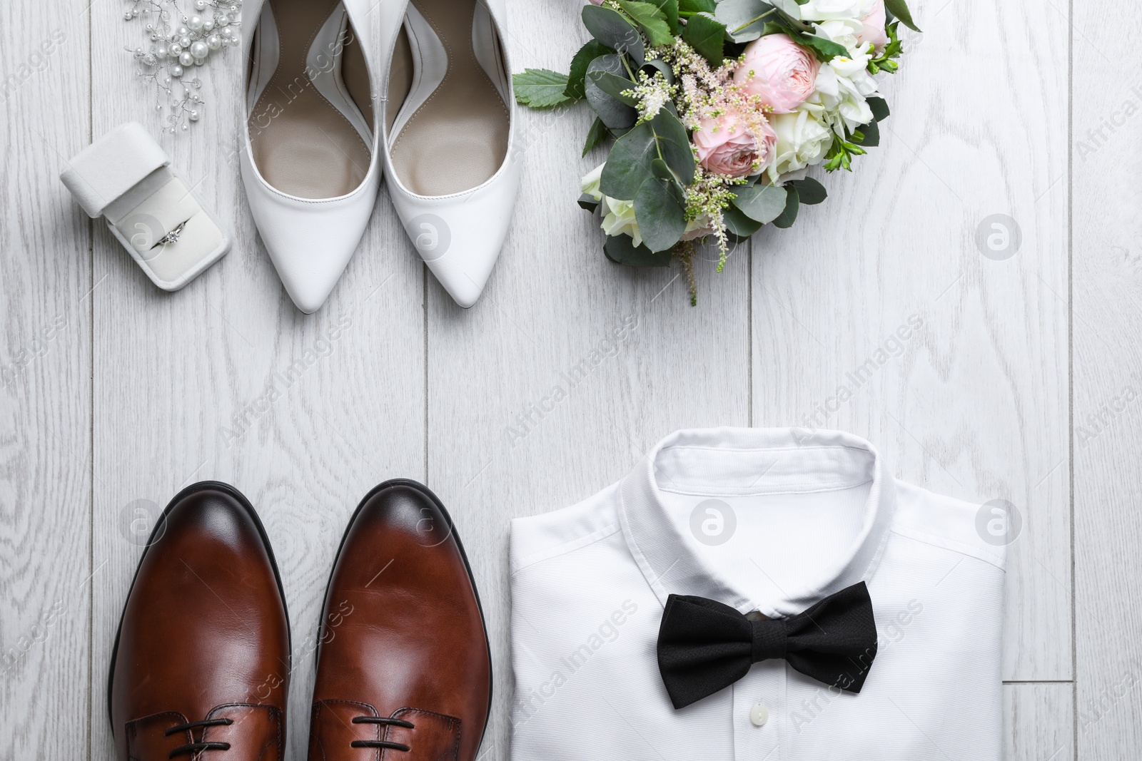 Photo of Flat lay composition with wedding shoes for bride and groom on white wooden floor