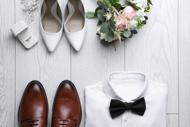 Flat lay composition with wedding shoes for bride and groom on white wooden floor