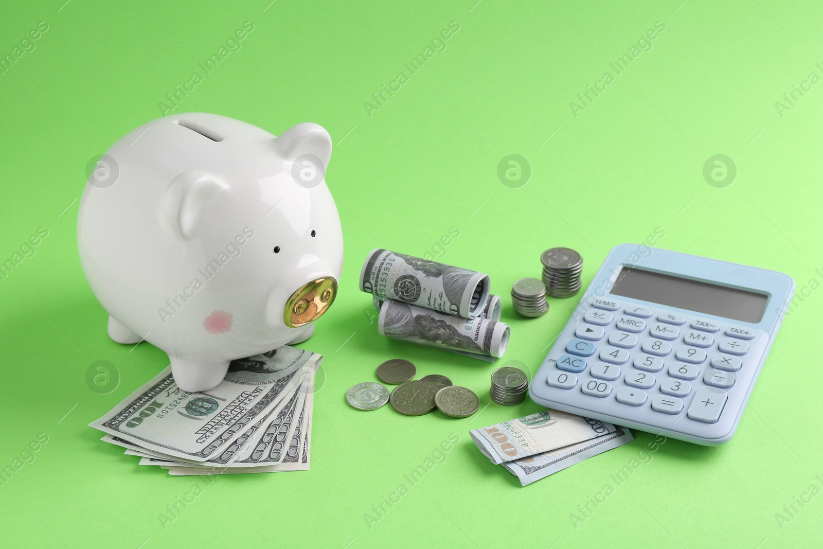 Photo of Financial savings. Piggy bank, dollar banknotes, coins and calculator on green background