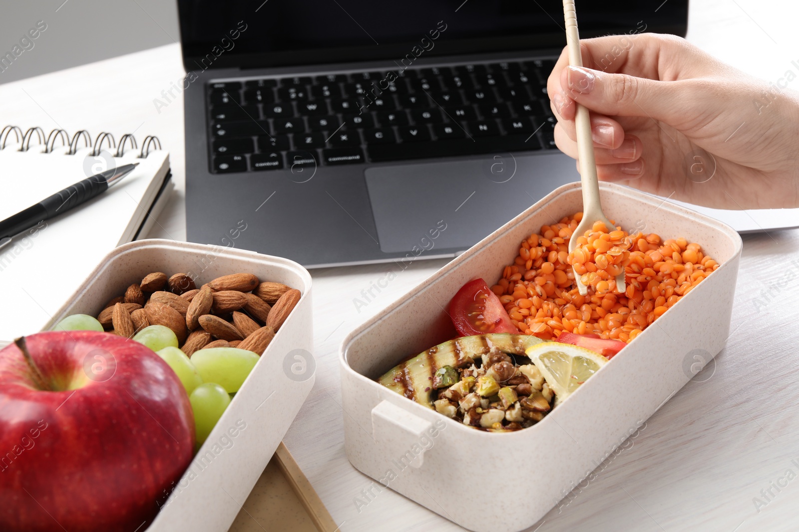 Photo of Woman eating healthy products high in vegetable fats near laptop at wooden table, closeup