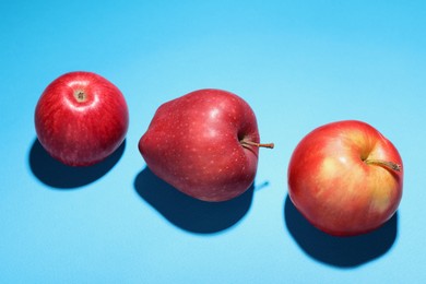 Photo of Ripe red apples on light blue background, closeup