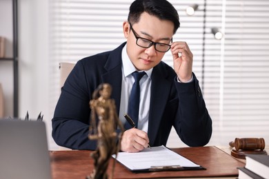 Photo of Notary writing notes at wooden table in office