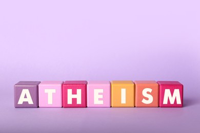 Word Atheism made of cubes with letters on violet background