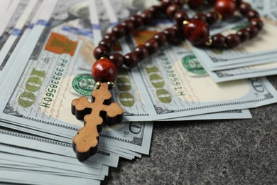 Photo of Wooden cross and money on grey table, closeup