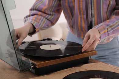 Photo of Young woman using turntable at home, closeup