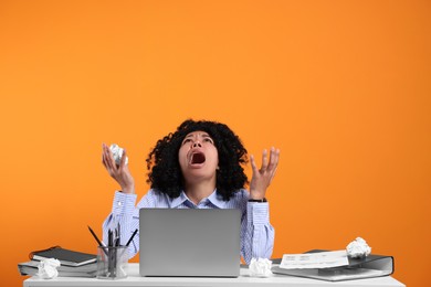 Photo of Stressful deadline. Emotional woman with crumpled paper shouting at white table against orange background. Space for text