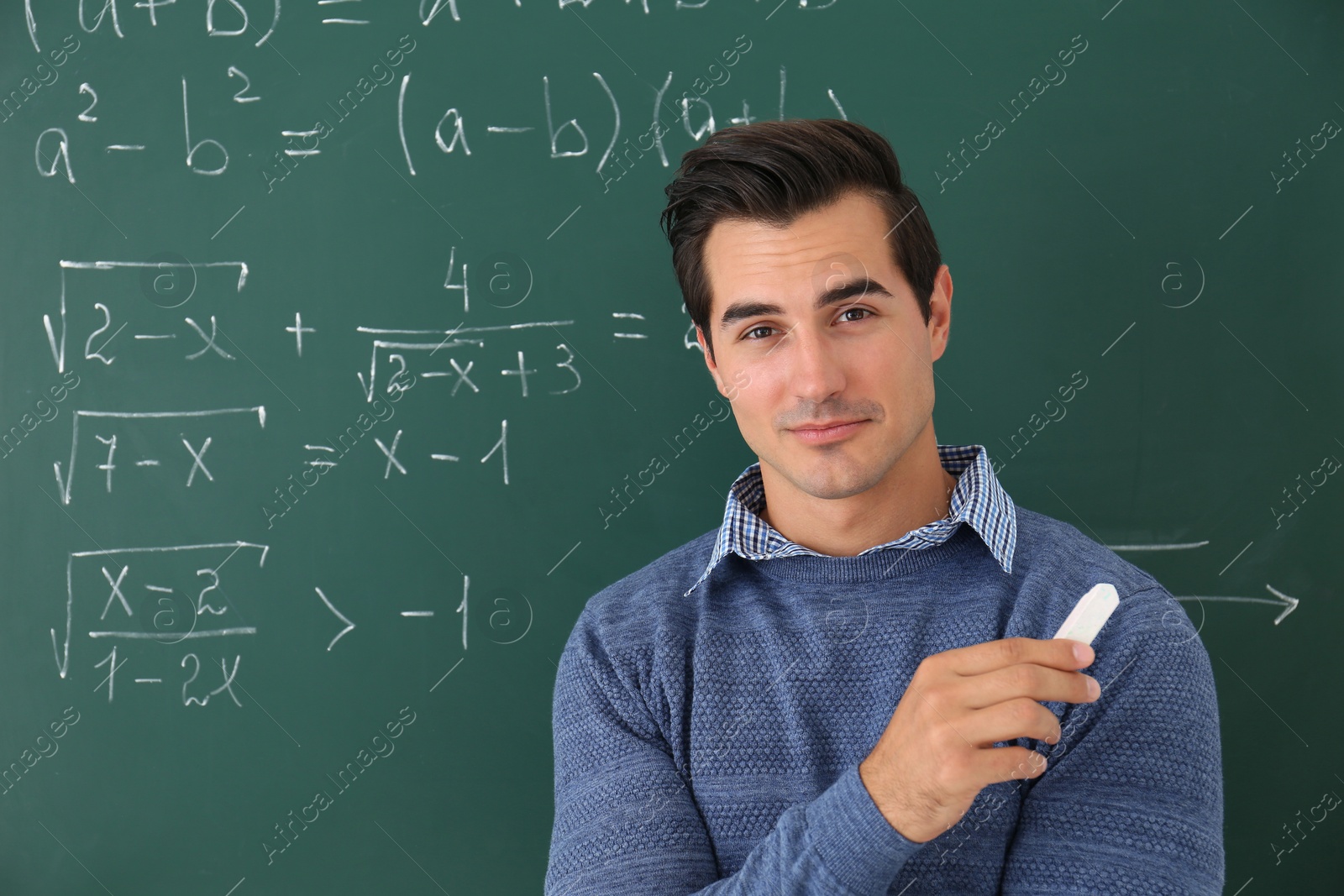 Photo of Young teacher near chalkboard with math formulas