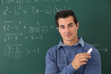 Photo of Young teacher near chalkboard with math formulas